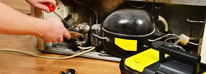 Refrigerator repair technician fixing the compressor and wiring in Hurst, TX