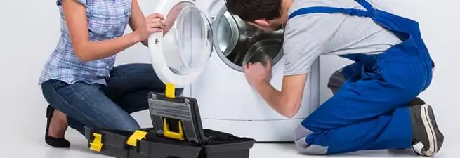 Washer repair technician inspecting a front-load washing machine with tools in Fort Worth, TX